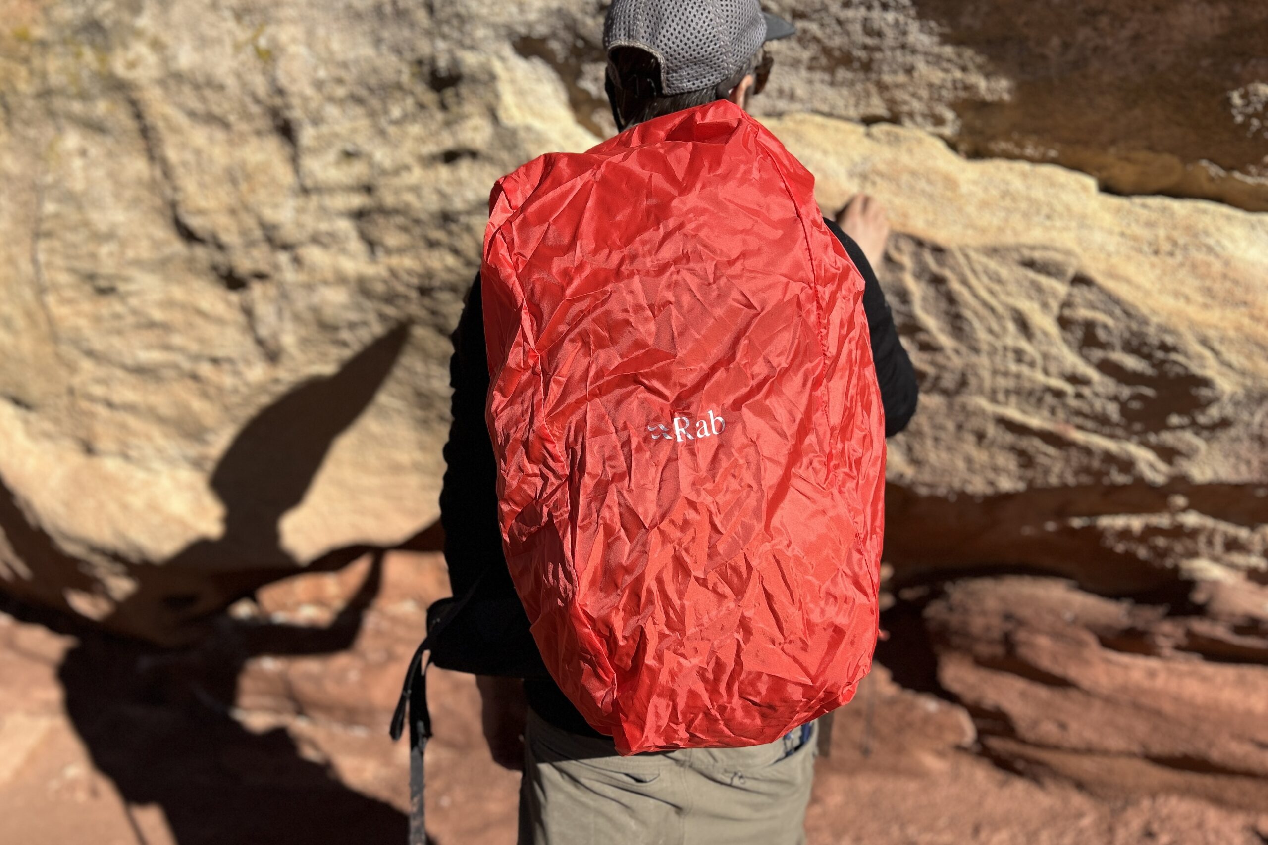 Close up shot of a person wearing a backpack with the raincover on from behind.