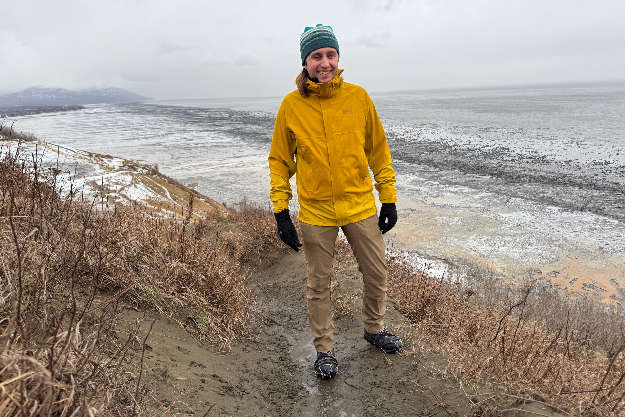 A man smiles while hiking in the rain.