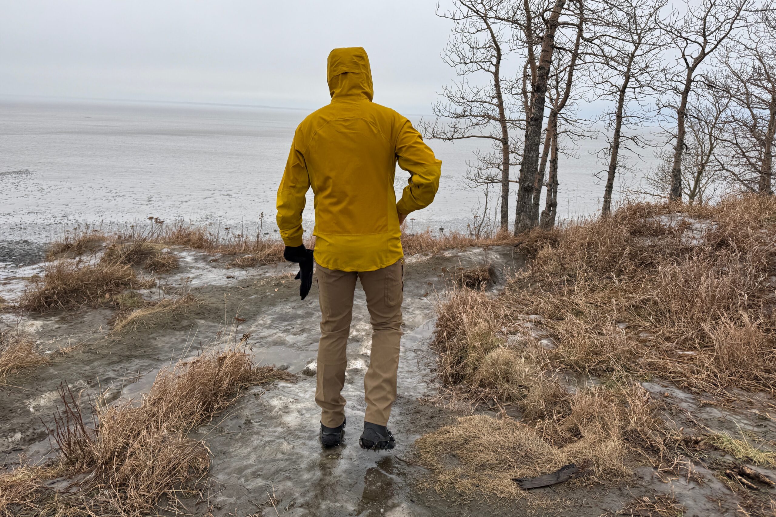 A man walks away from the camera on a rainy trail.