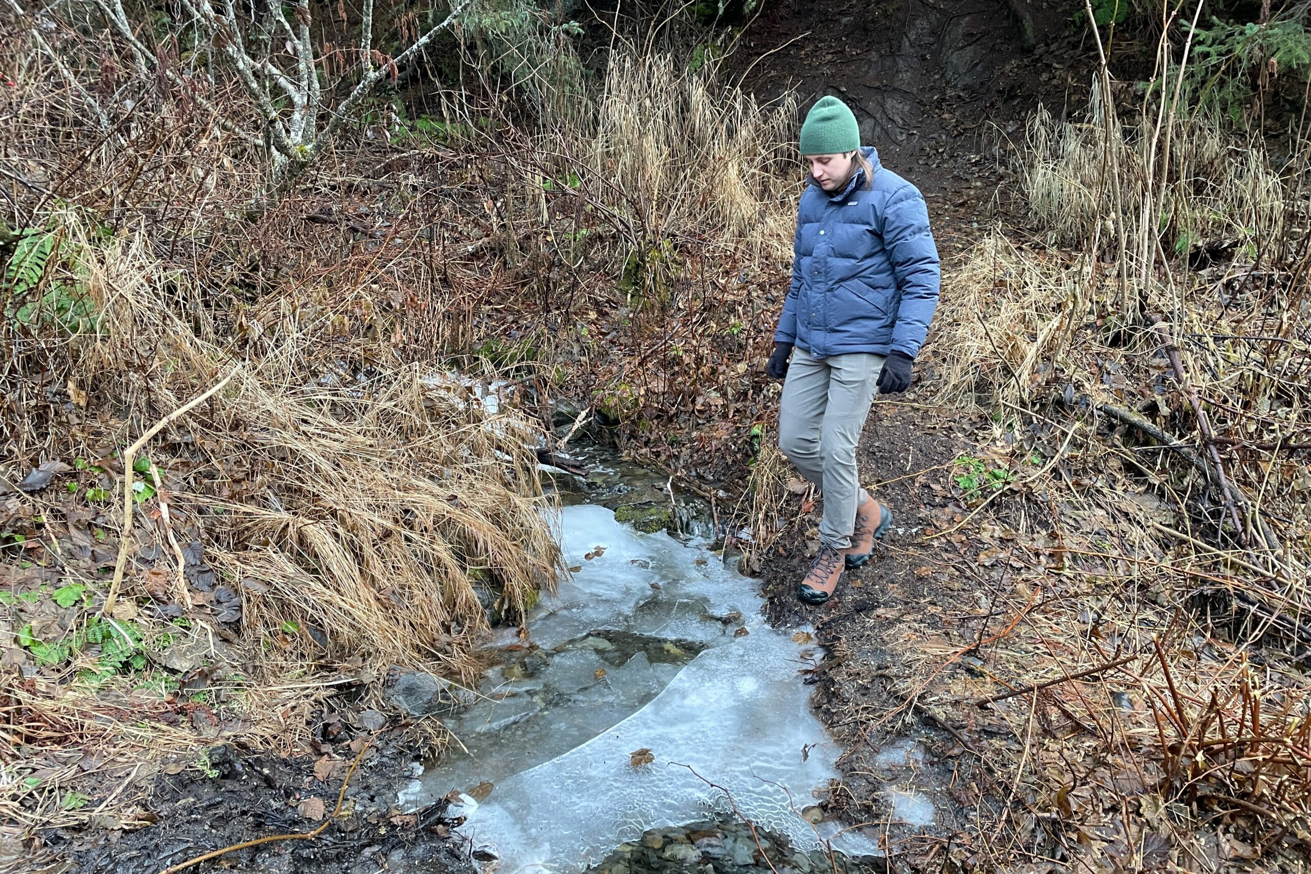 A man walks across a small, icy creek.