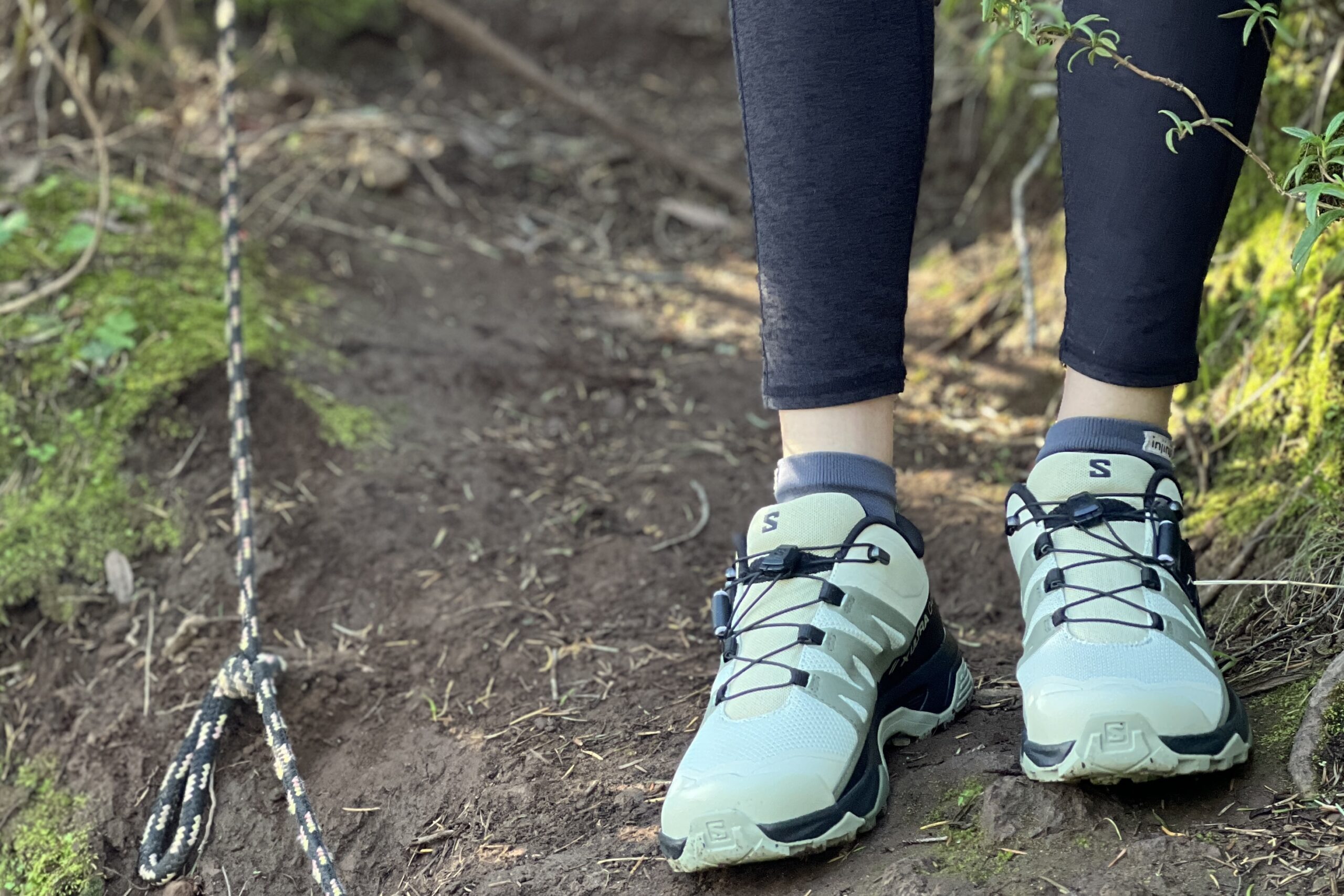 Close up of a woman standing on a trail wearing the Salomon X Ultra 4 shoes.