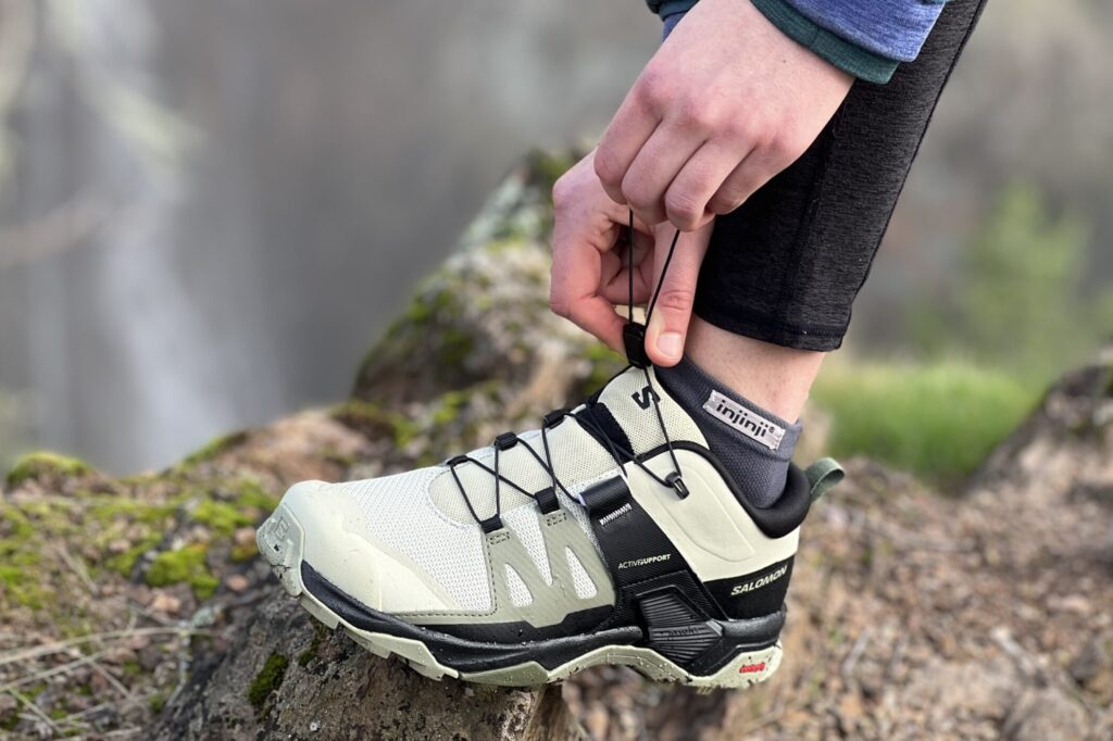 Close up of the Salomon X Ultra 4 Low shoe, while a woman cinches down the quick-lace system.