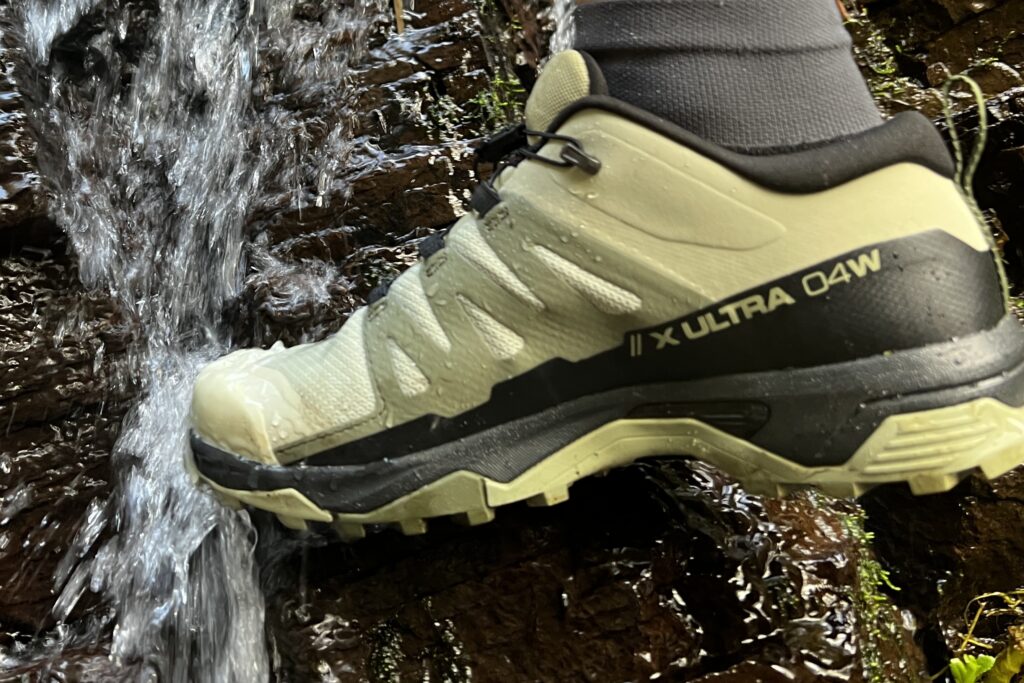 Close up of the Salomon X Ultra 4 Low as water falls over the uppers of the shoe.