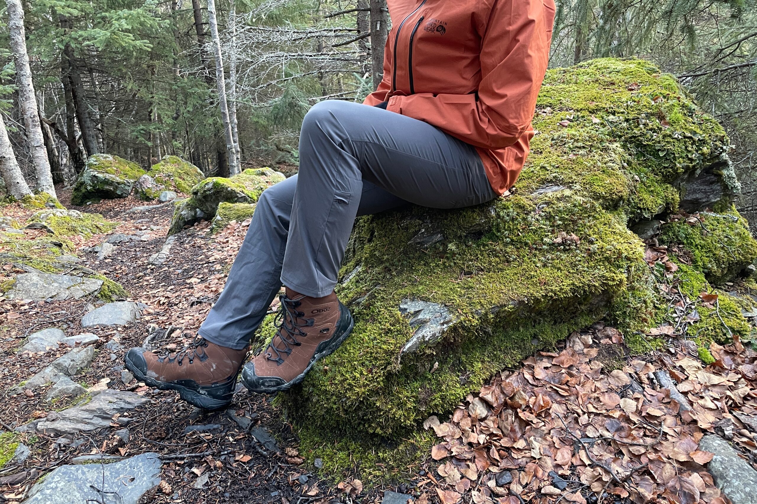 A man sits on a mossy rock.