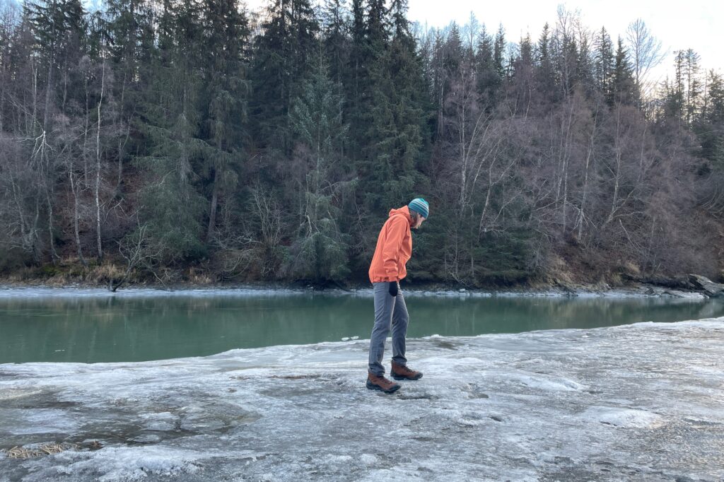 A man hikes along an icy river.