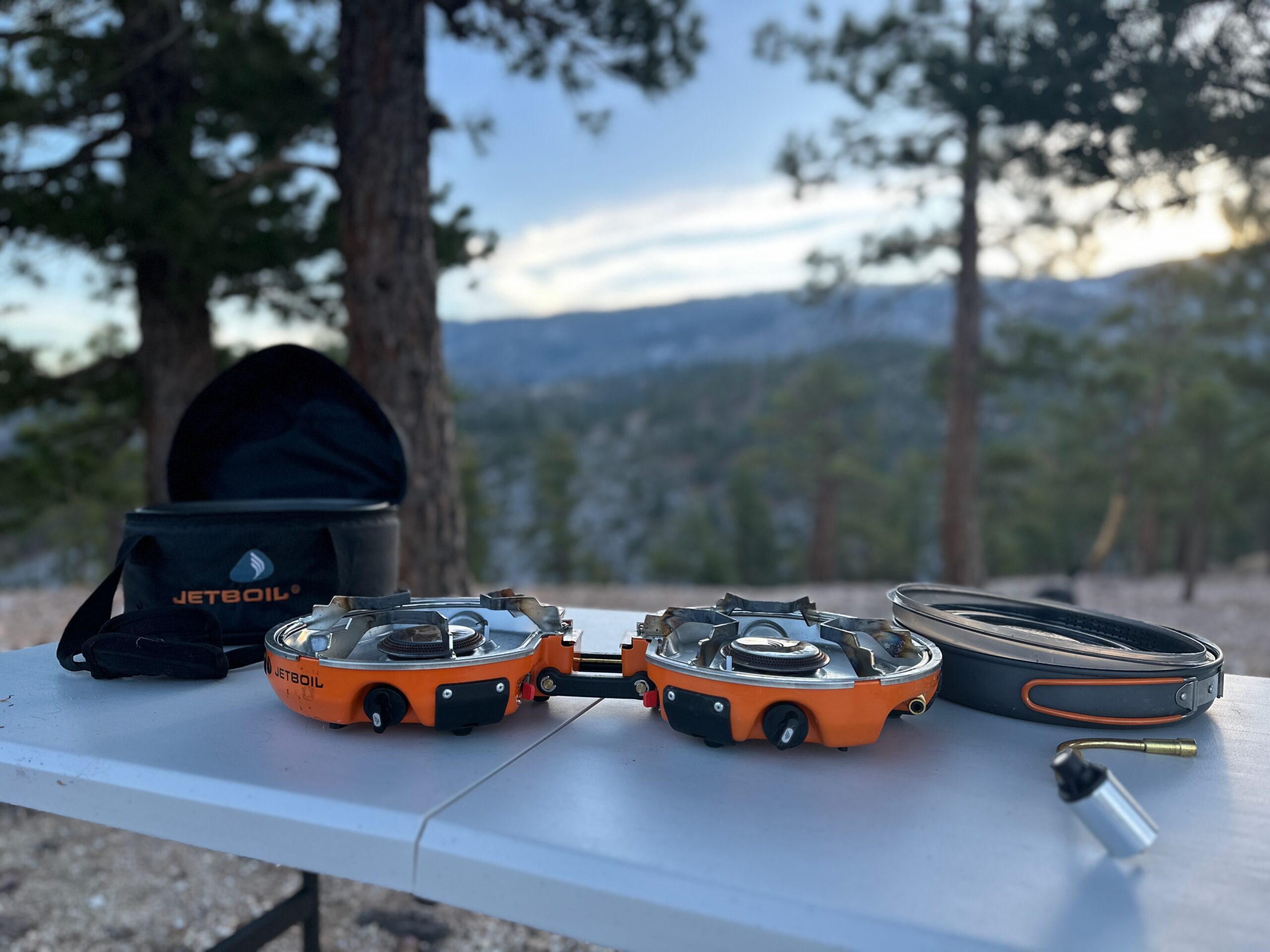 the Jetboil Genesis Basecamp System on a fold-out table in a high desert pine forest