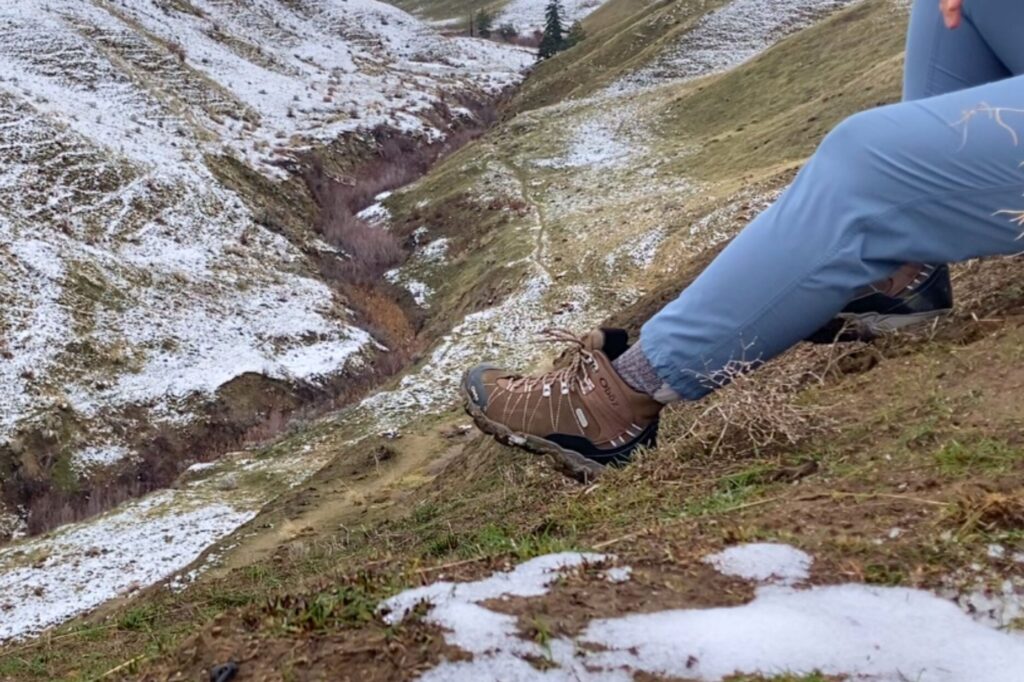 Hiker sitting on a hillside wearing the Women’s Oboz Bridger WP boots