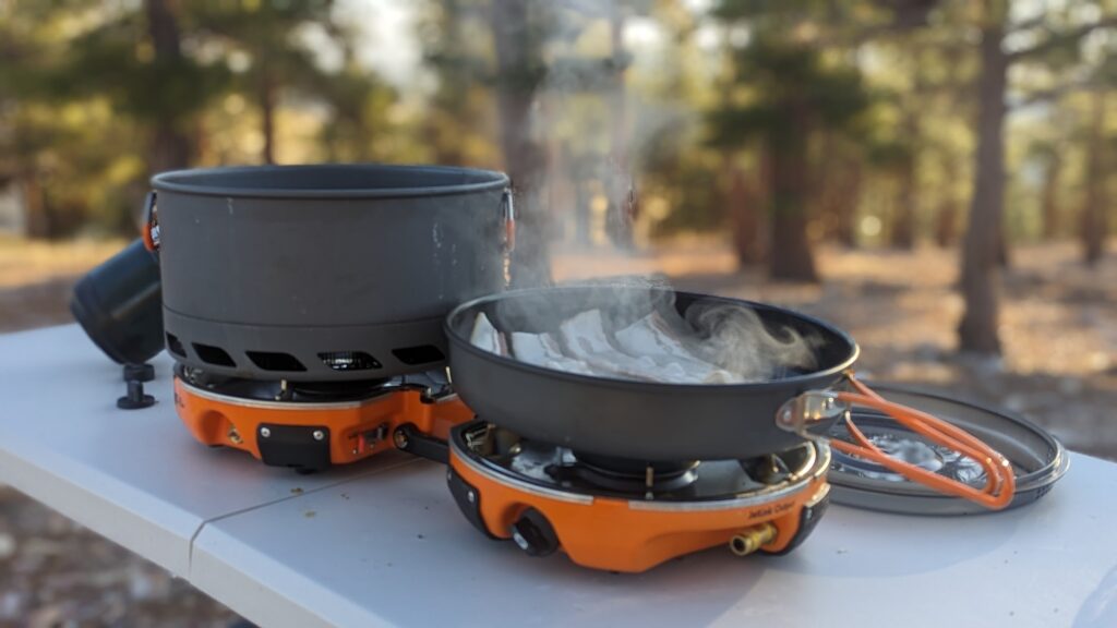 the Jetboil Genesis Basecamp System on a fold-out table in a high desert pine forest