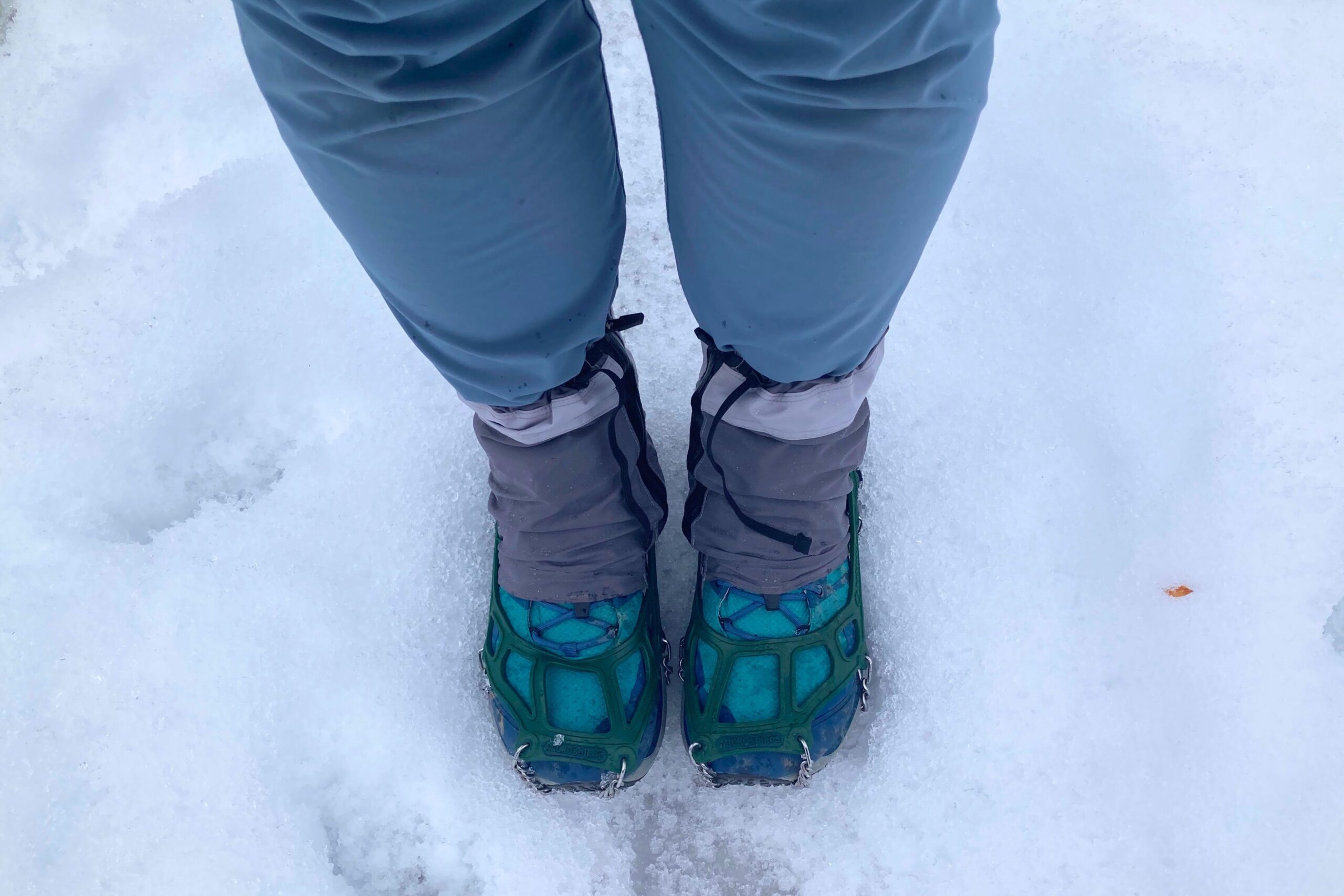 Hiker wearing the Women’s Topo Trailventure 2 WP in snow with gaiters and microspikes on