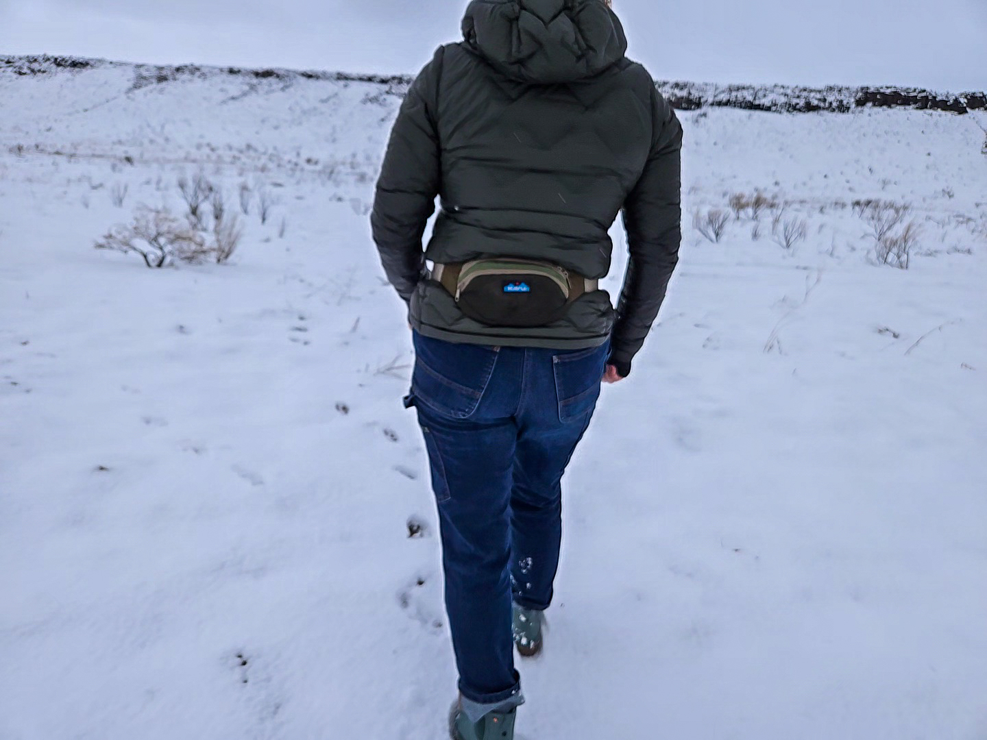 woman wearing a kavu spectator waist pack while walking on a snowy field