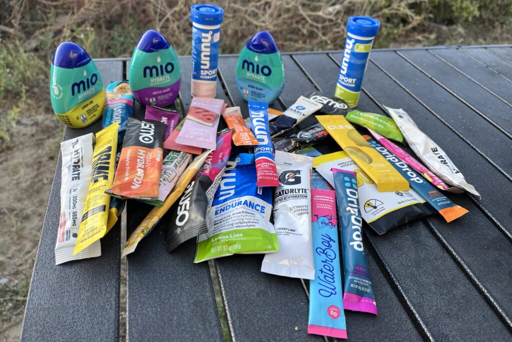 Semi-aerial view of dozens of electrolyte powders and mixes on a camping table