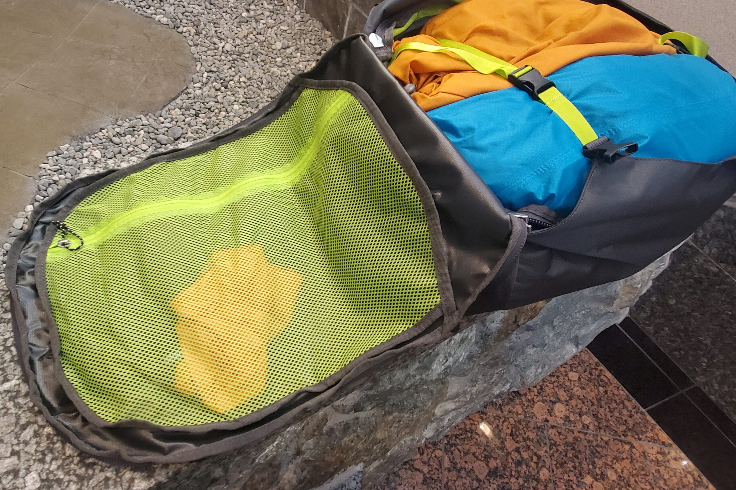 A backpack sits unzipped showing it's brightly colored interior.