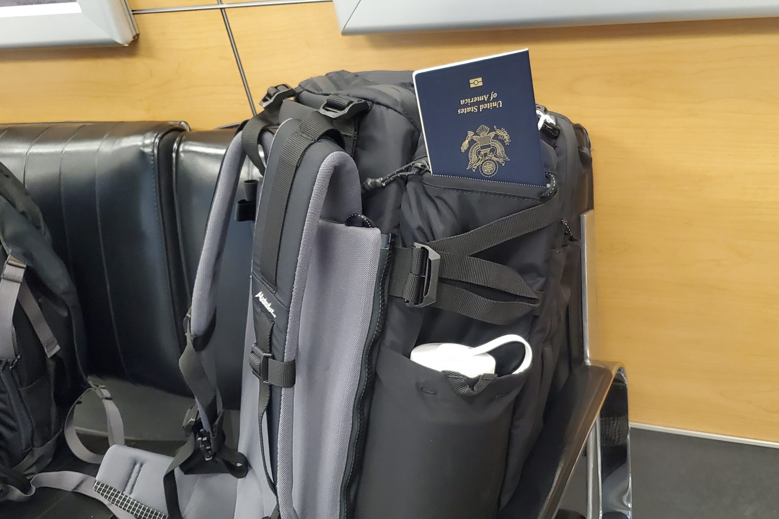 A backpack sits on a chair with a passport sticking out of a pocket.