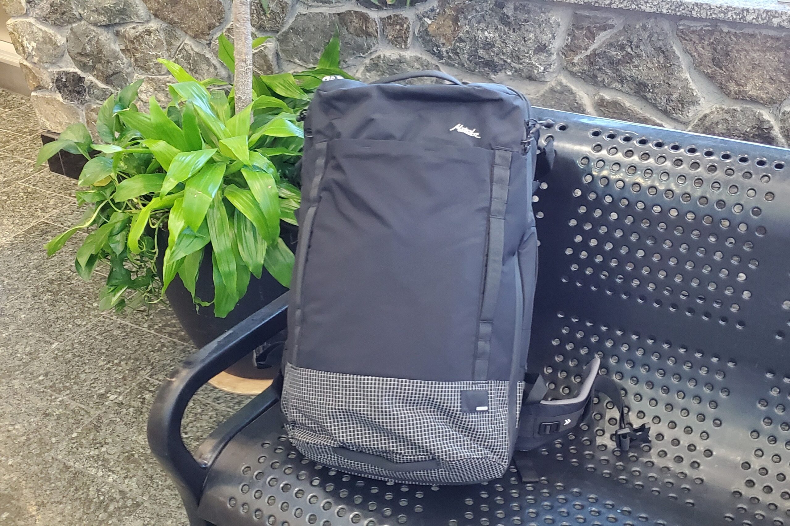 A black backpack sits on a bench in an airport.