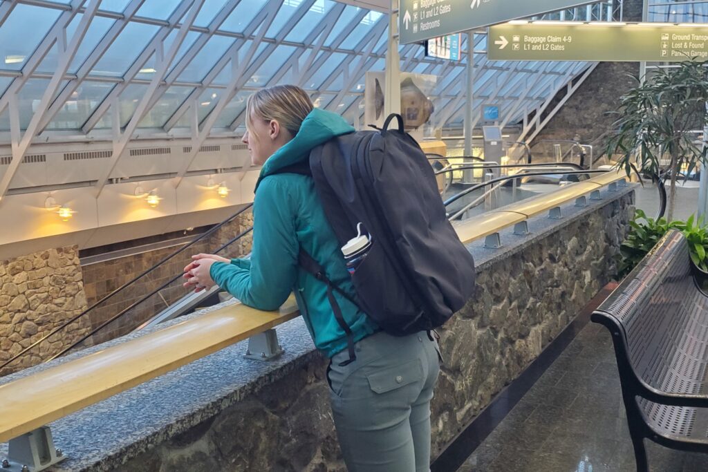 A woman leans against the railing in an airport terminal.