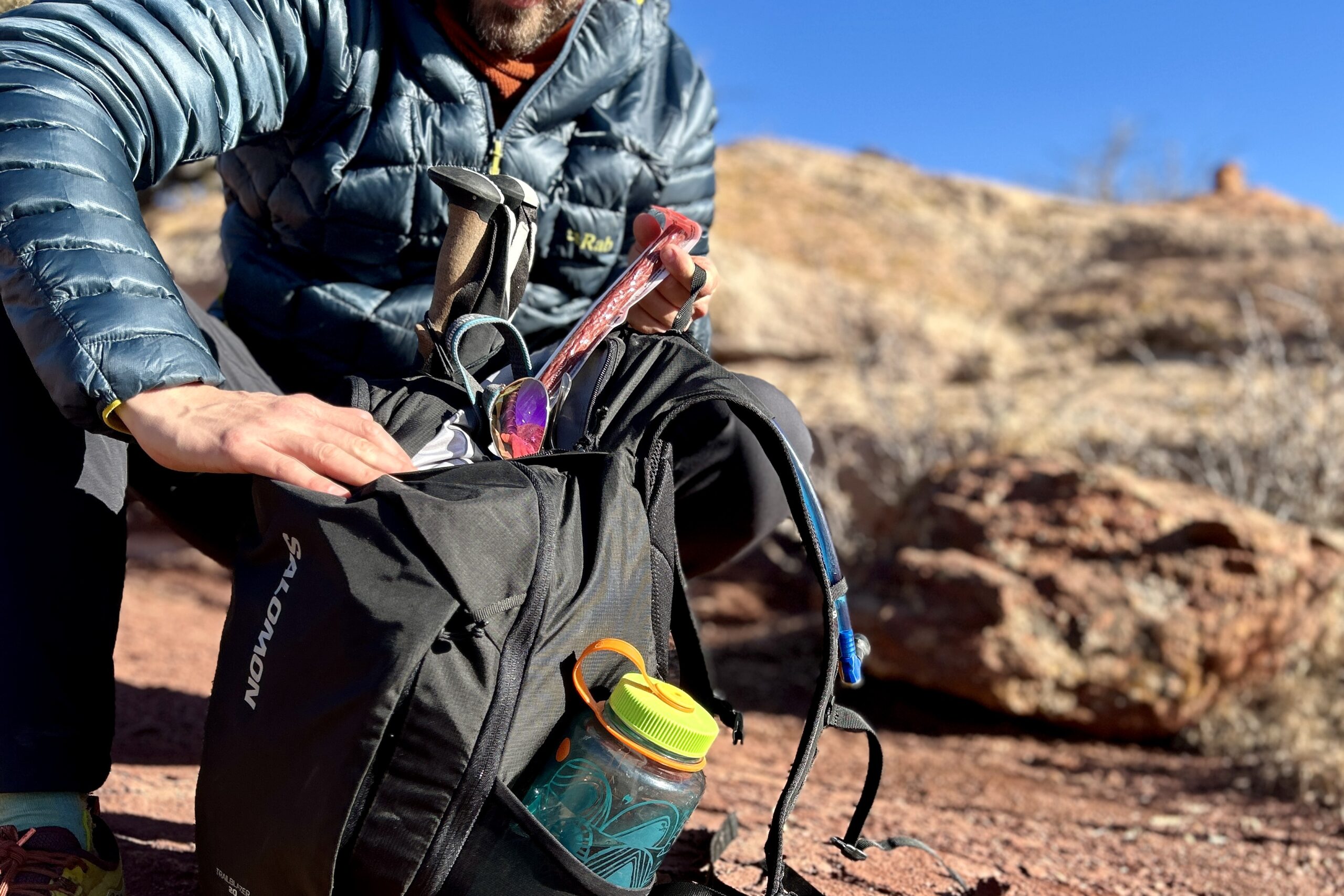 Close-up image of a person pulling items out of the top pocket of a daypack.