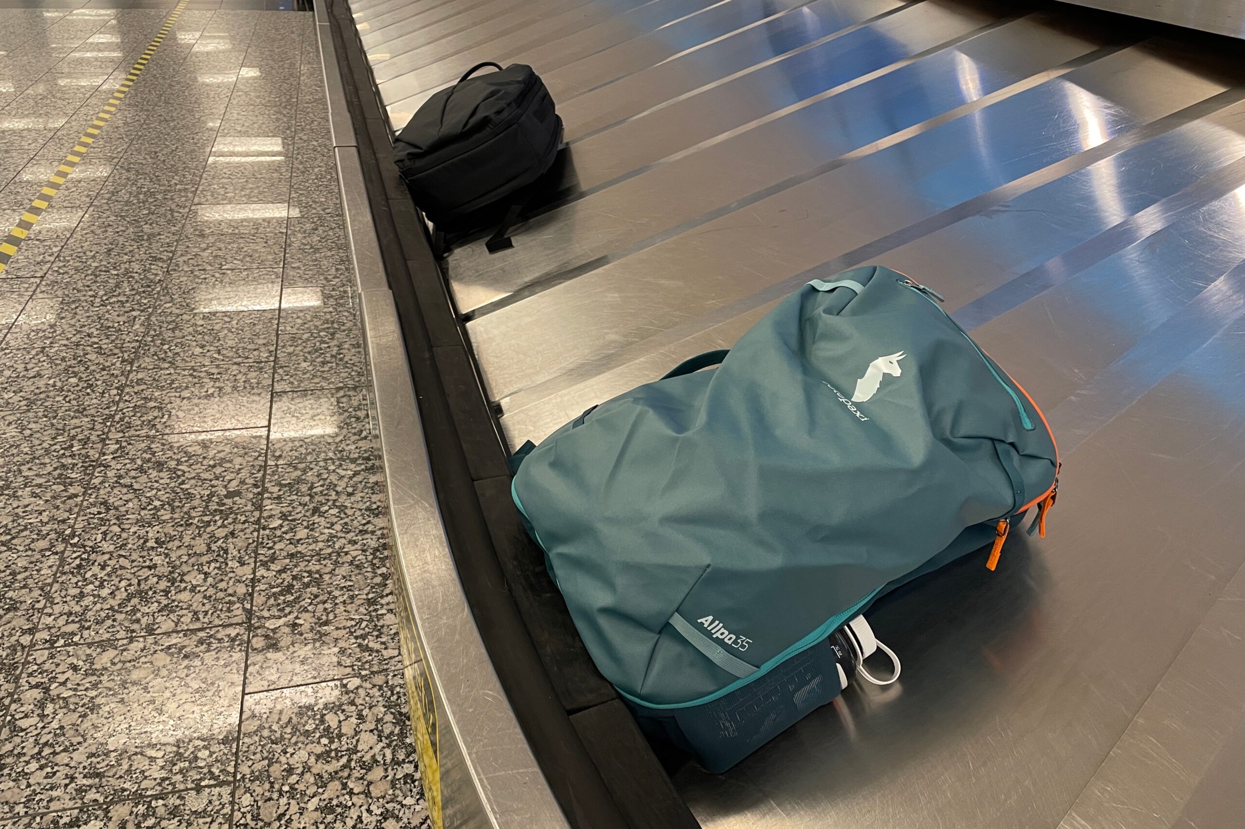 A green backpack sits on a baggage carousel.