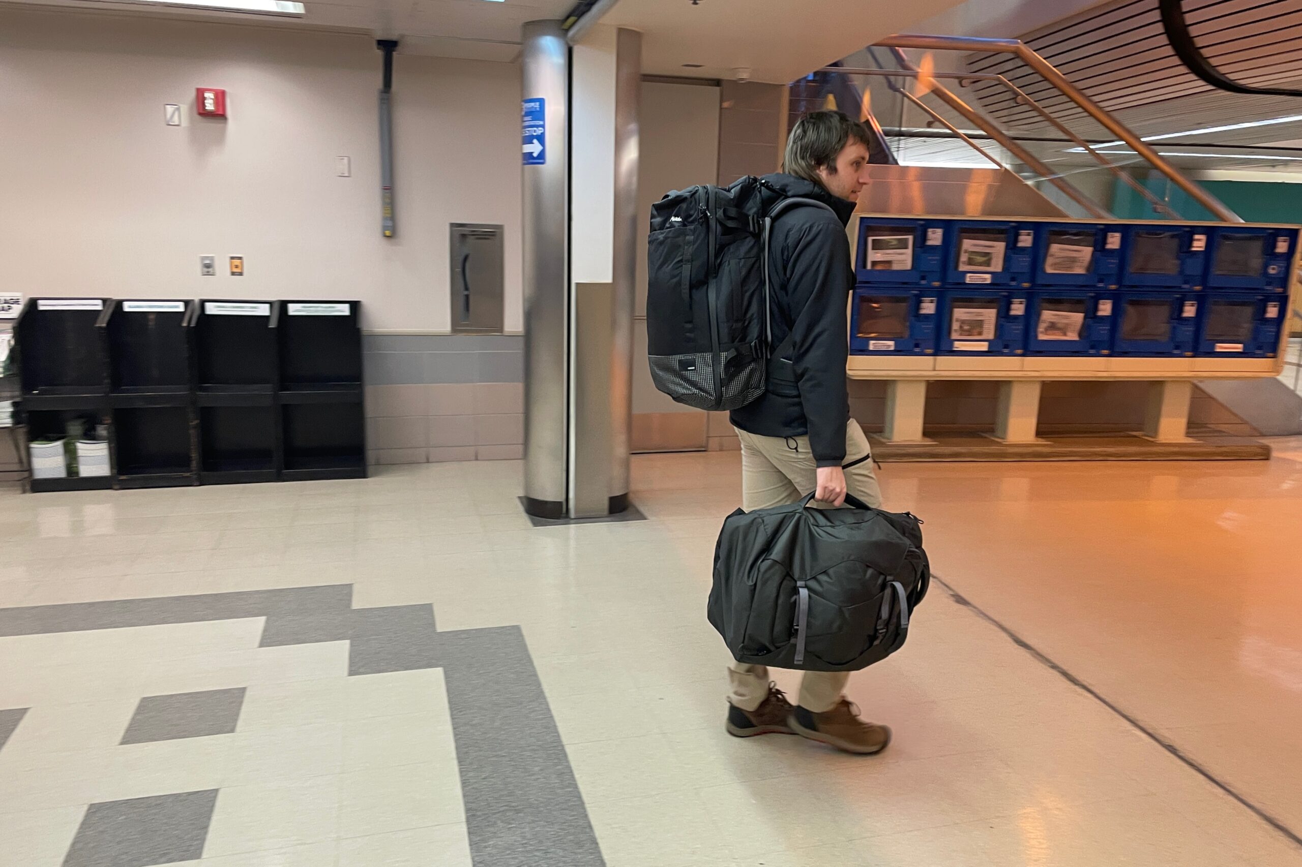 A man walks through an airport carrying luggage.