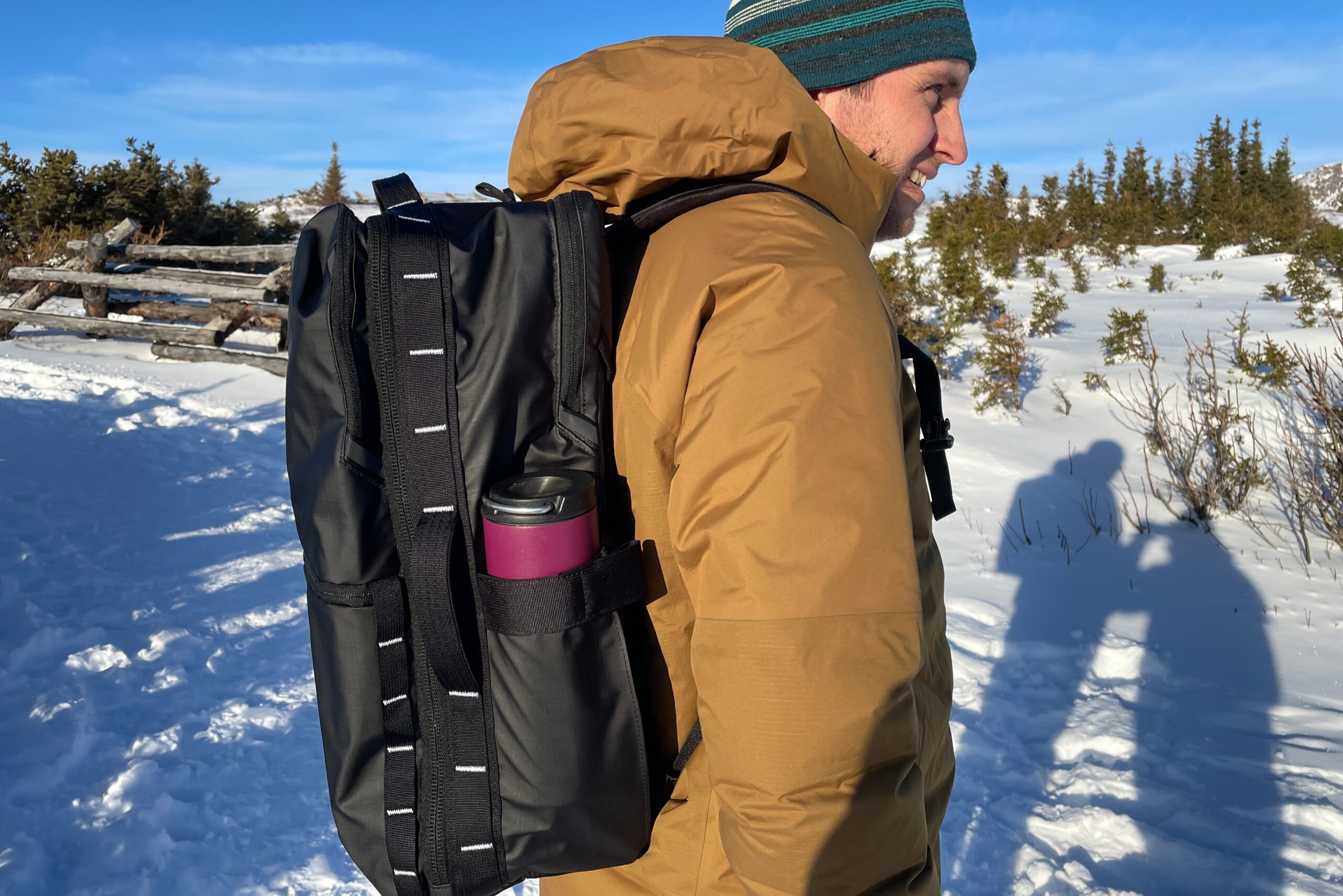 A side shot of a man wearing a black backpack.