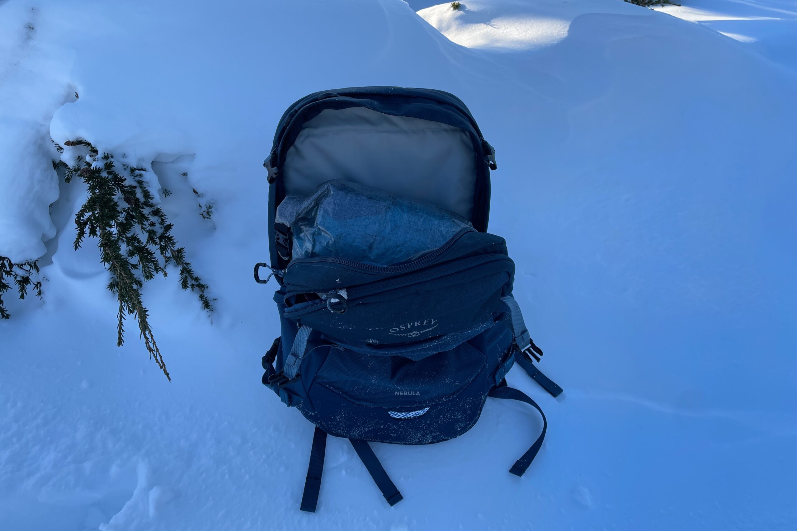 A backpack sit unzipped on the snow.