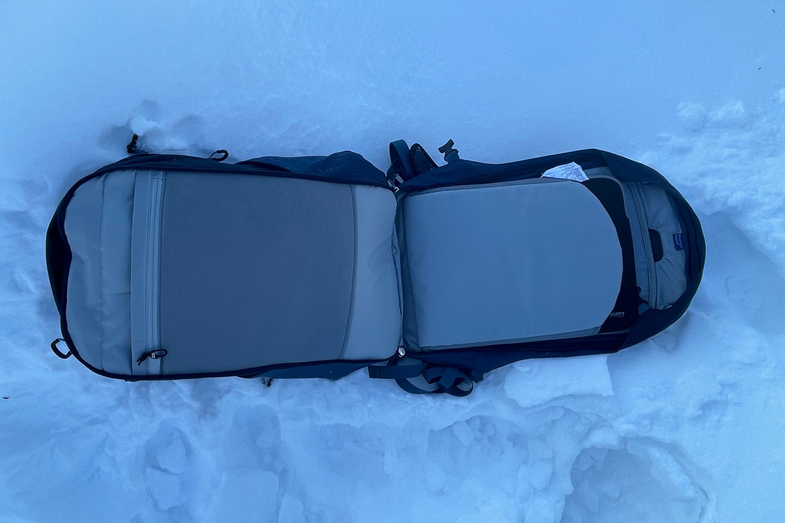 A backpack lays fully unzipped on the snow.