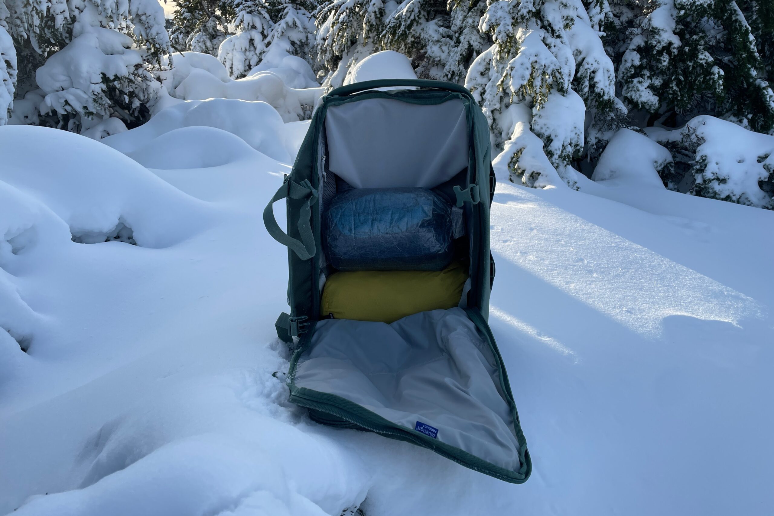 A backpack sits unzipped with packing bags inside/