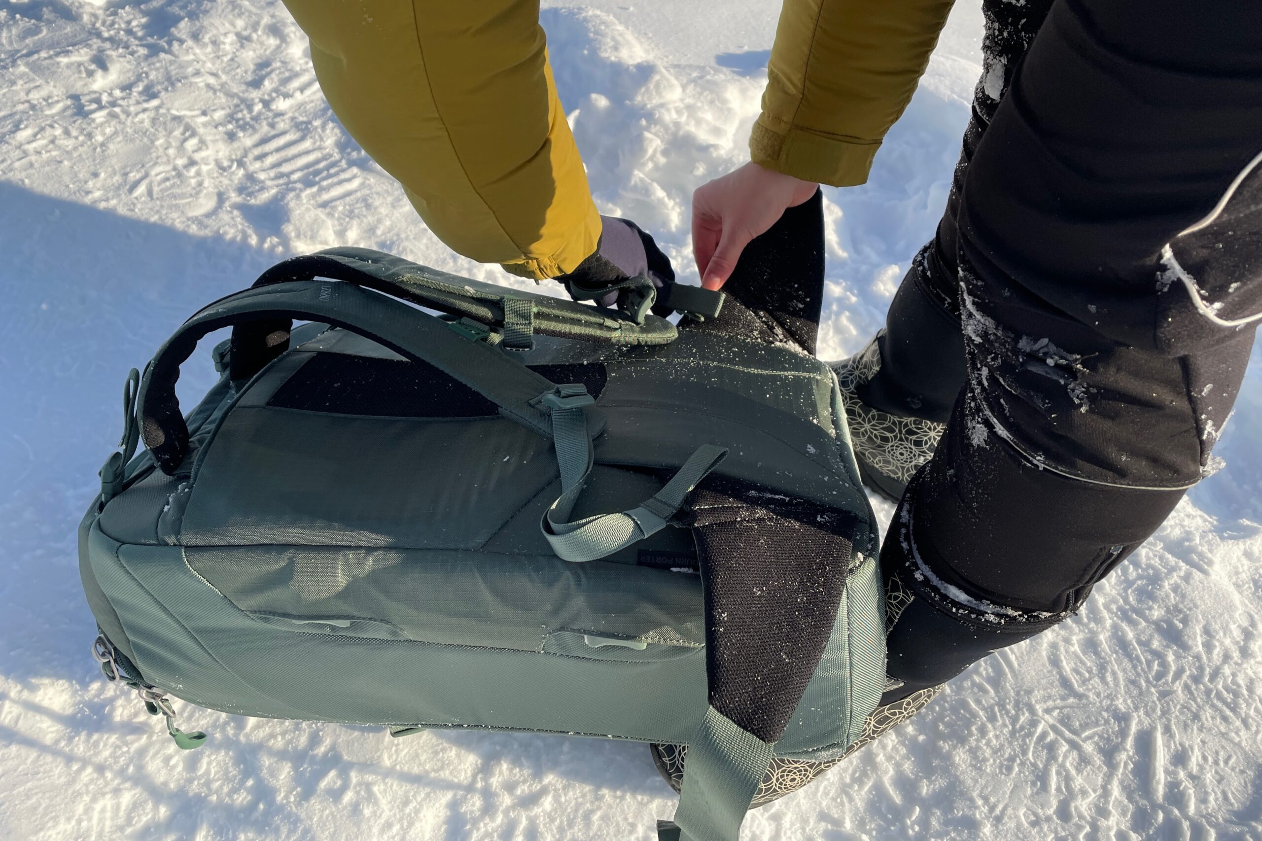 A closeup of a backpack's shoulder straps being unclipped.