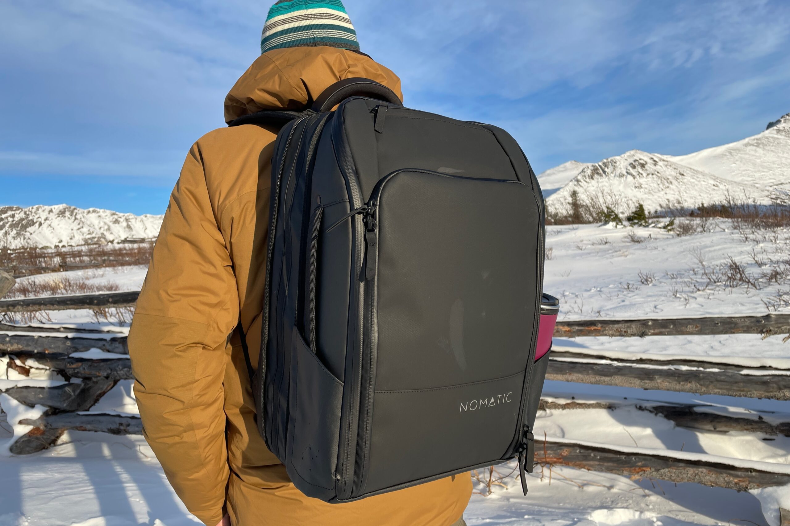 A man stands back to the camera in a snowy landscape.