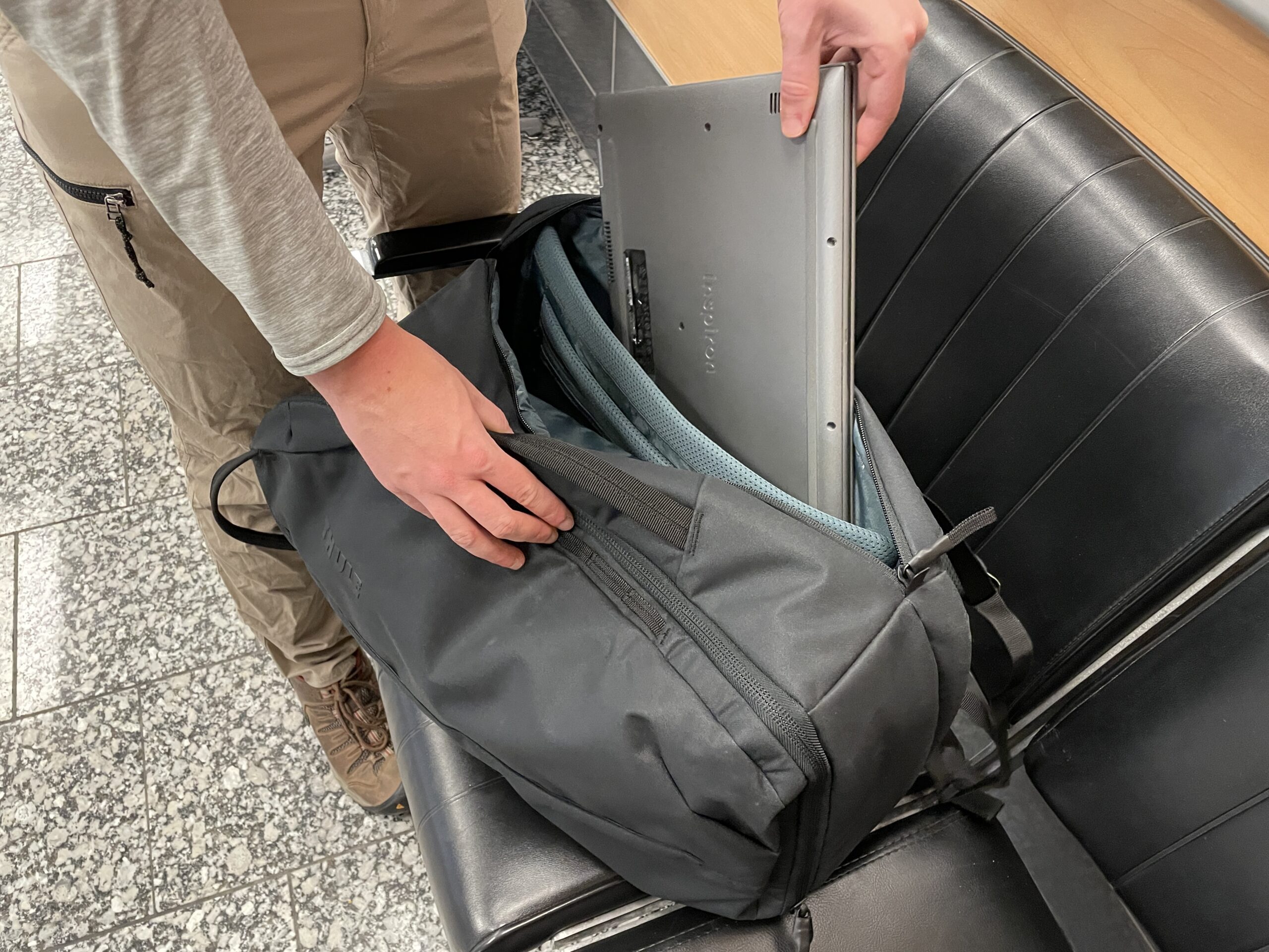 A man places a laptop inside of the compartment of a backpack.